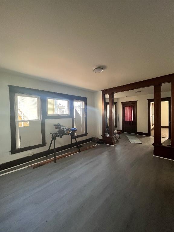 interior space with decorative columns, plenty of natural light, baseboards, and dark wood-style flooring