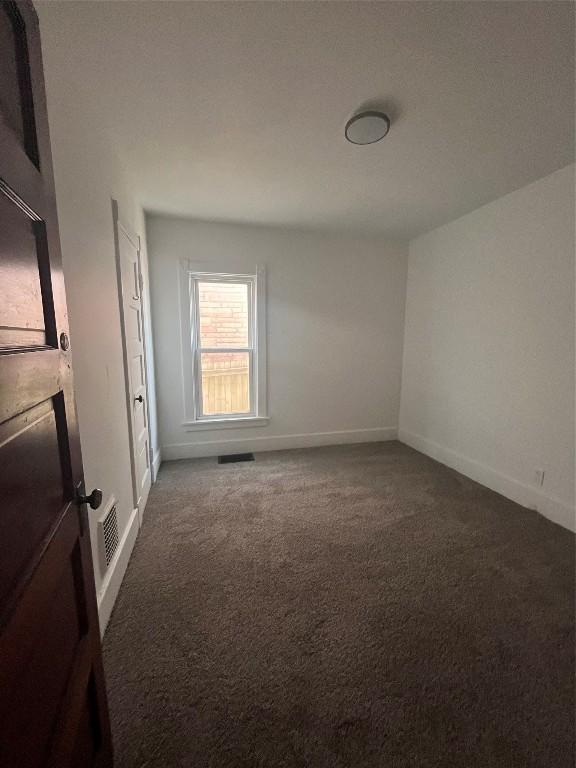 unfurnished room with carpet, visible vents, and baseboards