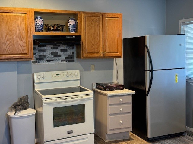 747 E 25th St, Erie, PA 16503 - kitchen with freestanding refrigerator, white range with electric stovetop, under cabinet range hood, wood finished floors, and brown cabinetry