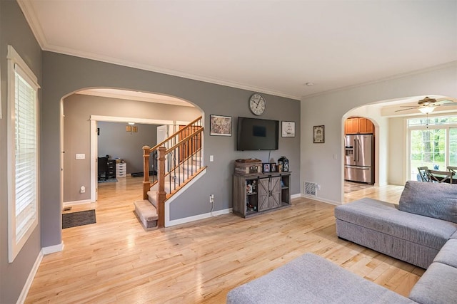 21720 Matthew Ln, Saegertown, PA 16433 - living area with arched walkways, light wood finished floors, crown molding, stairs, and a ceiling fan