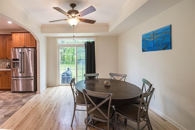 21720 Matthew Ln, Saegertown, PA 16433 - dining area featuring baseboards, arched walkways, a ceiling fan, light wood-type flooring, and crown molding