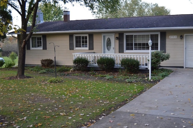 single story home featuring a garage, a front yard, and covered porch