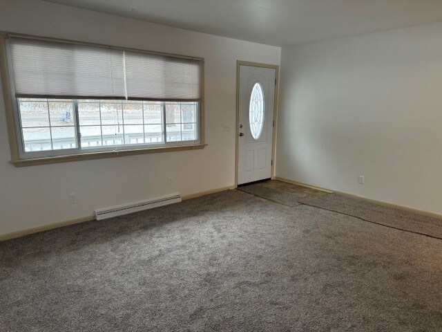 carpeted foyer featuring a baseboard heating unit