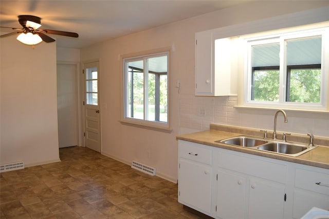 kitchen with tasteful backsplash, ceiling fan, sink, and white cabinets