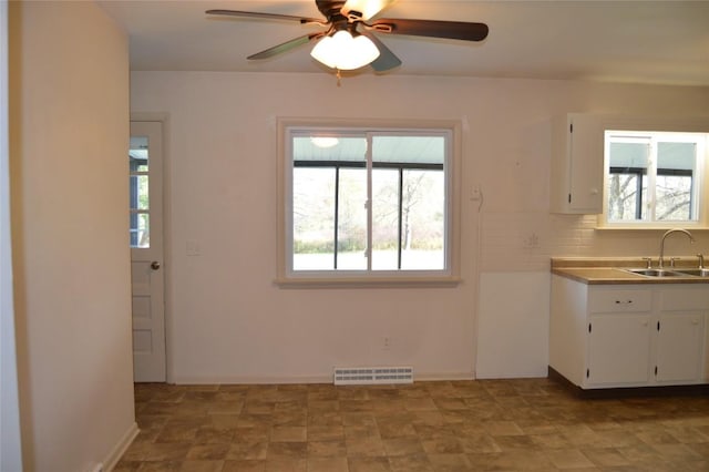 kitchen with tasteful backsplash, sink, white cabinets, and ceiling fan