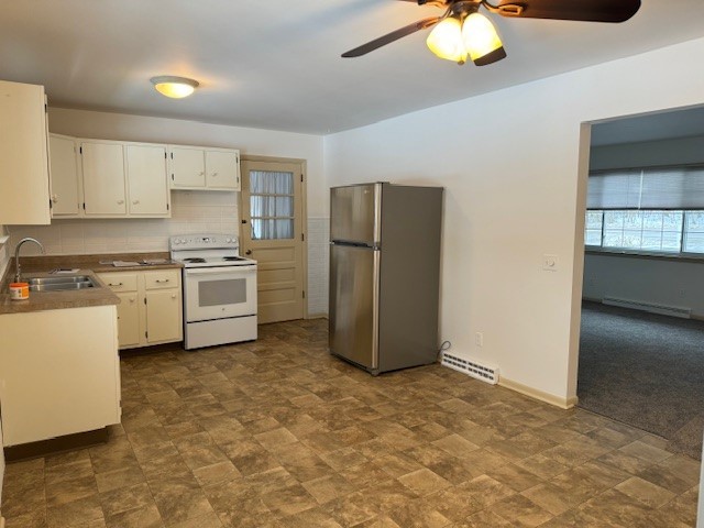 kitchen featuring sink, white cabinets, stainless steel fridge, decorative backsplash, and electric range