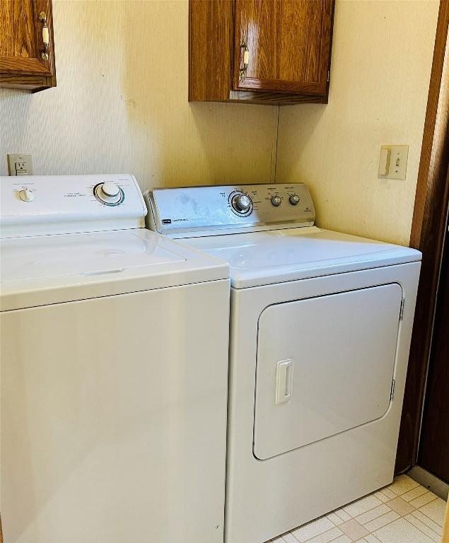 clothes washing area with separate washer and dryer and cabinet space