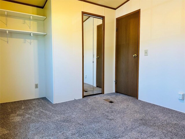 unfurnished bedroom featuring a closet, carpet flooring, crown molding, and visible vents