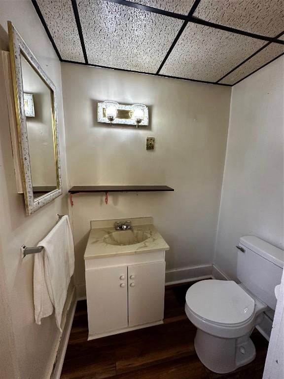 bathroom with a paneled ceiling, wood finished floors, and toilet