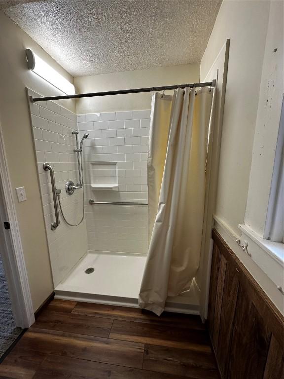 bathroom featuring a shower with shower curtain, a textured ceiling, and wood finished floors