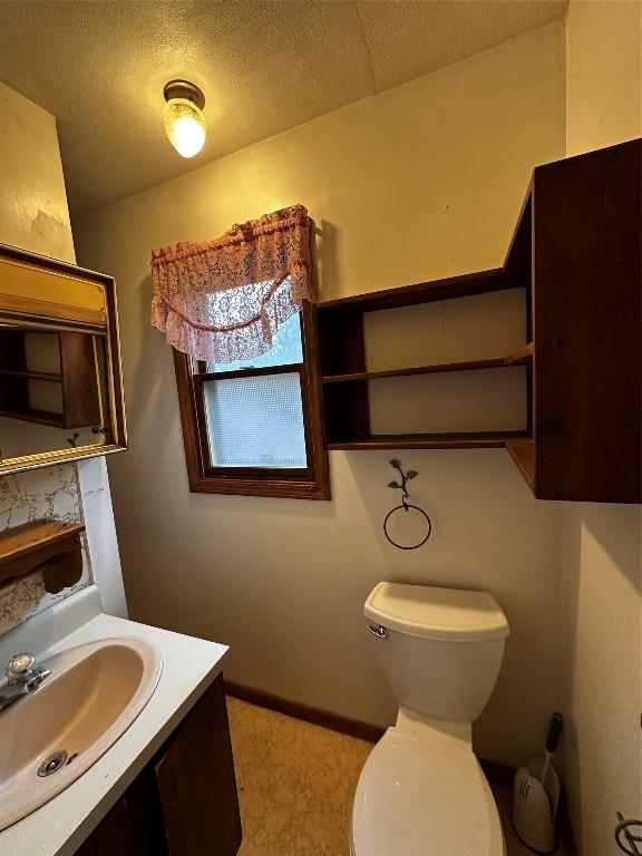 bathroom with vanity, toilet, and a textured ceiling