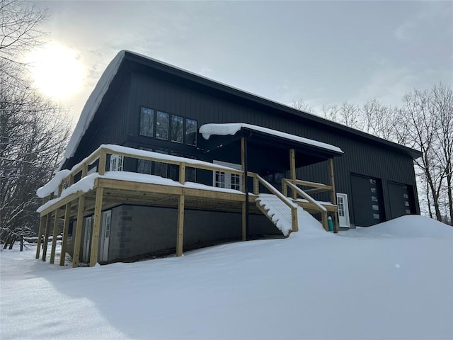 snow covered back of property featuring a garage