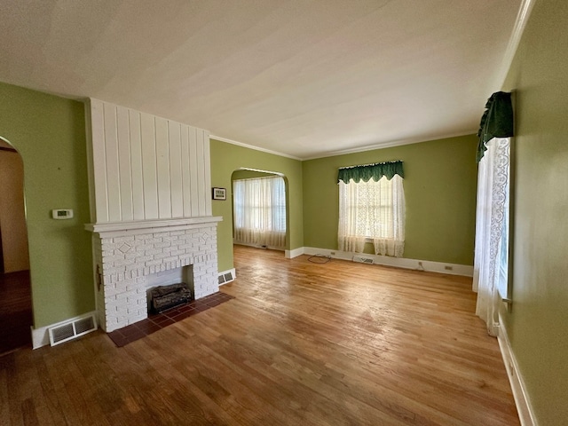957 E 29th St, Erie, PA 16504 - unfurnished living room featuring arched walkways, wood finished floors, a brick fireplace, and ornamental molding