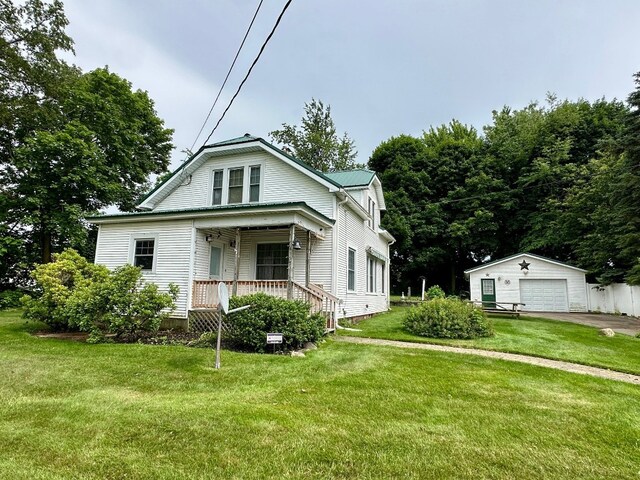 957 E 29th St, Erie, PA 16504 - view of front of house with covered porch, an outbuilding, a detached garage, a front lawn, and a metal roof