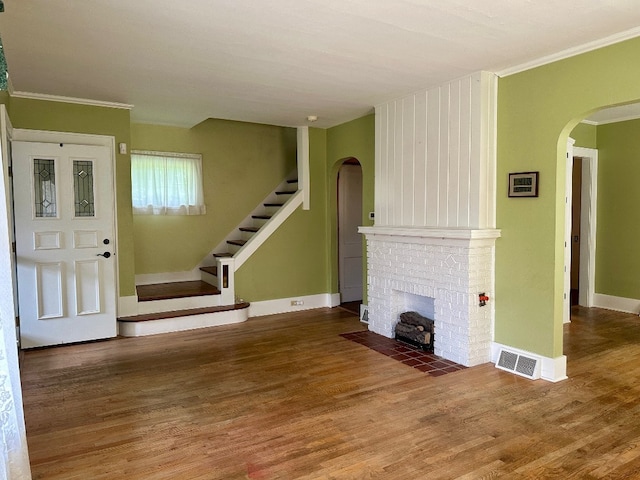957 E 29th St, Erie, PA 16504 - unfurnished living room with arched walkways, wood finished floors, ornamental molding, a brick fireplace, and stairway