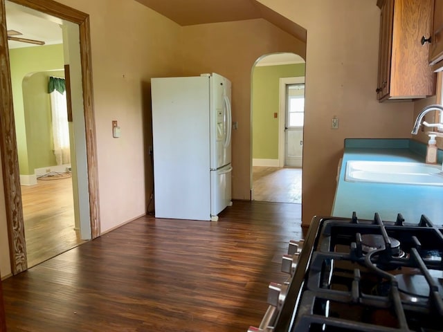 957 E 29th St, Erie, PA 16504 - kitchen featuring white fridge with ice dispenser, arched walkways, dark wood-style flooring, gas stove, and brown cabinets