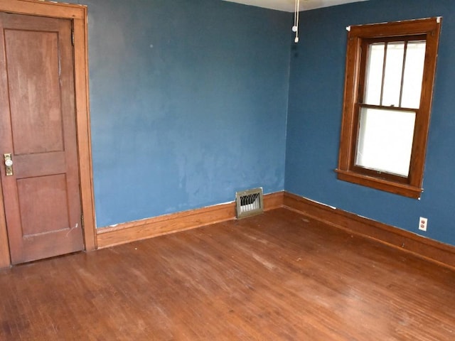 unfurnished room featuring baseboards, wood finished floors, and visible vents