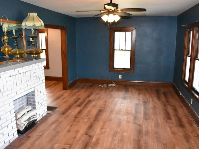 unfurnished living room featuring baseboards, a brick fireplace, ceiling fan, and wood finished floors