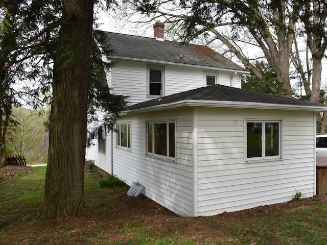 view of side of home featuring a chimney and roof with shingles