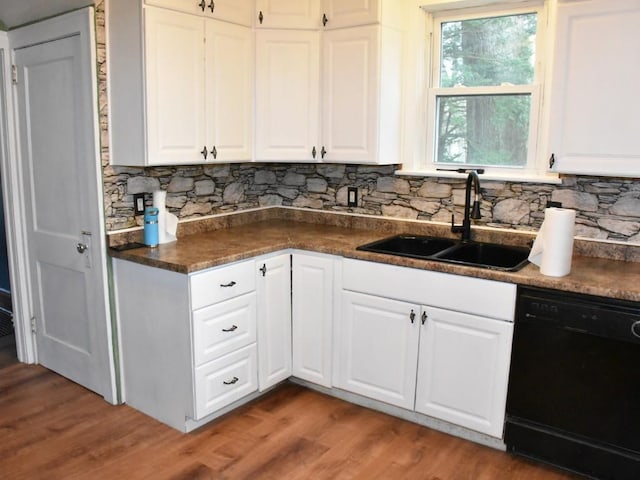kitchen featuring black dishwasher, dark countertops, decorative backsplash, and a sink