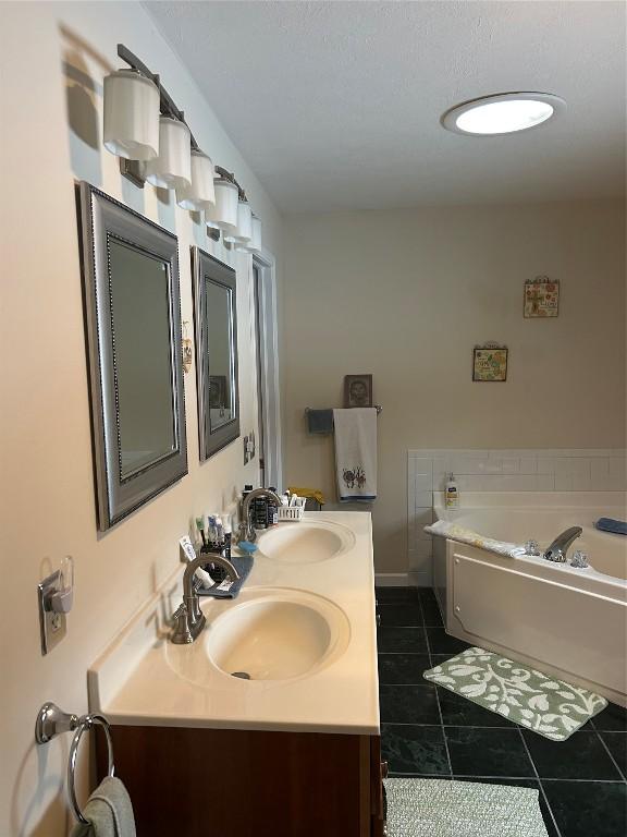 bathroom with tile patterned flooring, vanity, and a tub to relax in