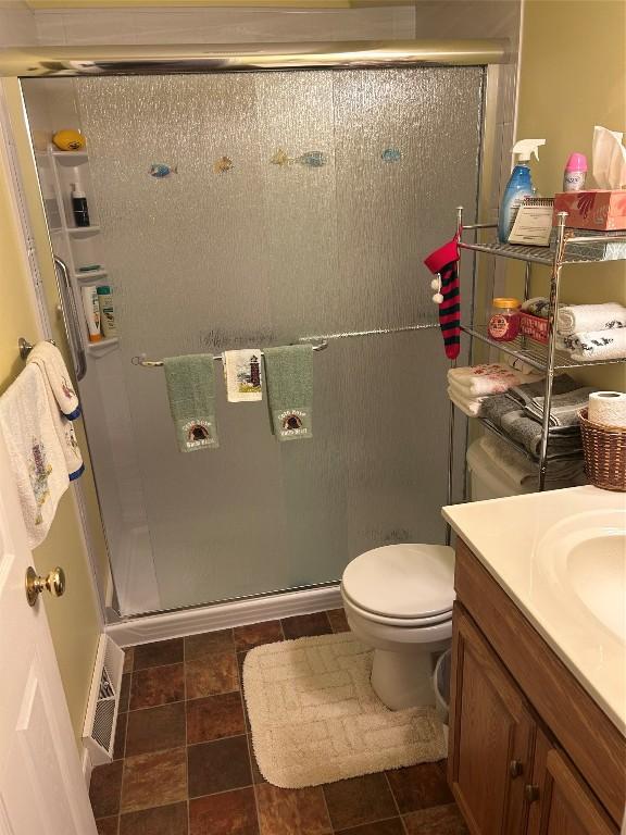 bathroom with vanity, toilet, and a shower with door