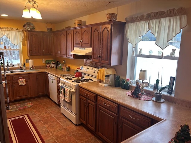 kitchen featuring white appliances, sink, and an inviting chandelier