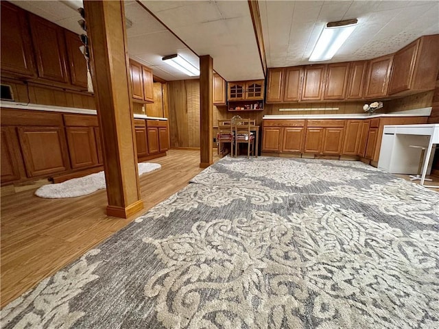 interior space with wooden walls, built in desk, and light hardwood / wood-style flooring