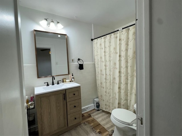 bathroom featuring tile walls, hardwood / wood-style floors, a shower with shower curtain, vanity, and toilet