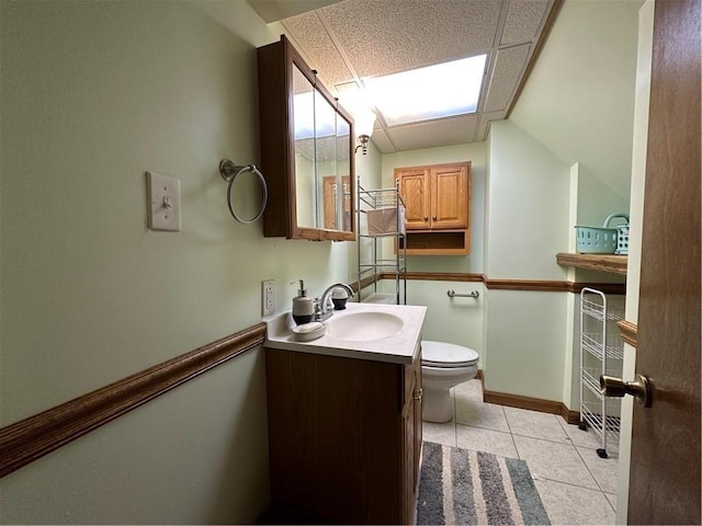 bathroom with tile patterned flooring, vanity, a paneled ceiling, and toilet