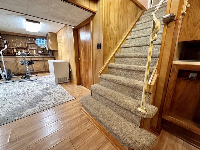 stairs with wood-type flooring and wooden walls