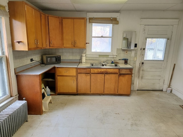 kitchen with a paneled ceiling, decorative backsplash, radiator heating unit, and sink