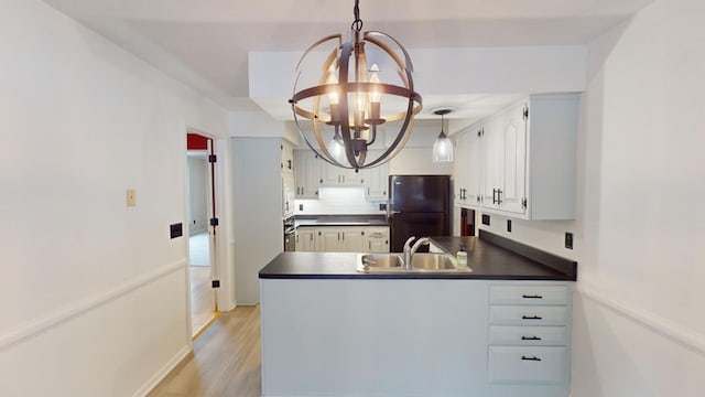 kitchen with black refrigerator, sink, a notable chandelier, white cabinets, and hanging light fixtures