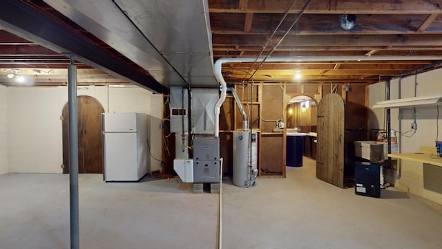 basement featuring white fridge, heating unit, and water heater