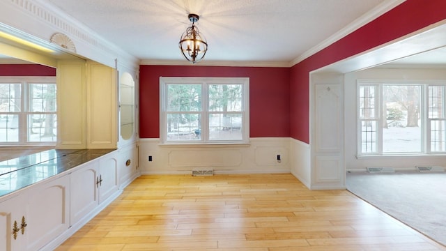 interior space featuring a wealth of natural light, crown molding, light hardwood / wood-style flooring, and an inviting chandelier