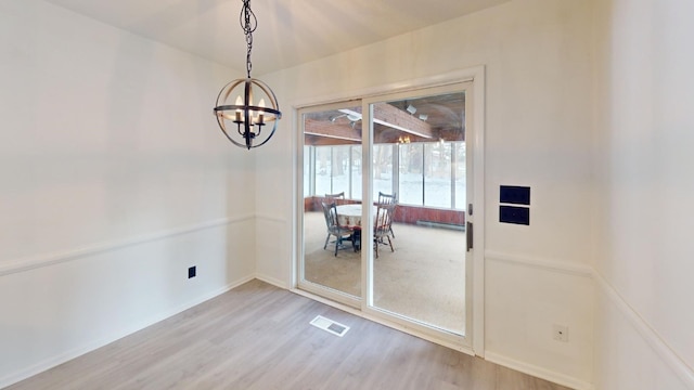 unfurnished dining area featuring a notable chandelier and wood-type flooring