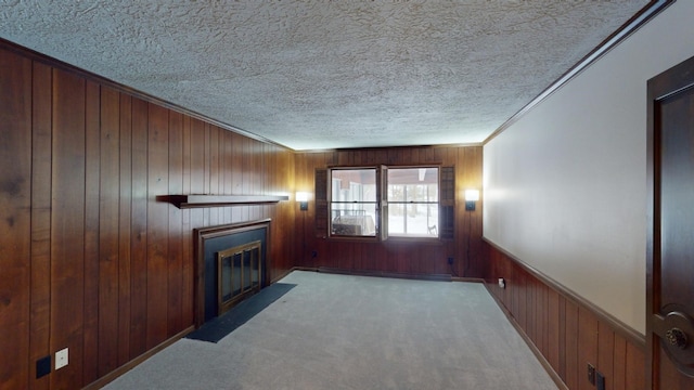 unfurnished living room with ornamental molding, a textured ceiling, light colored carpet, wooden walls, and a baseboard radiator