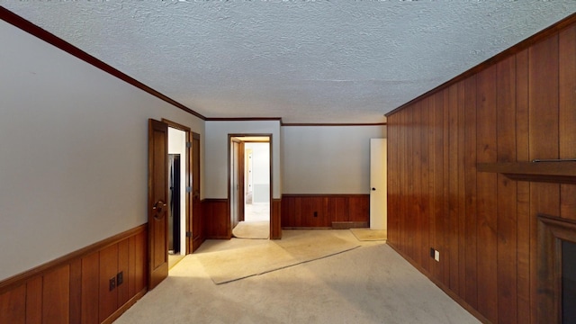 unfurnished room featuring a textured ceiling, light colored carpet, and ornamental molding