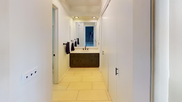 corridor featuring sink and light tile patterned flooring