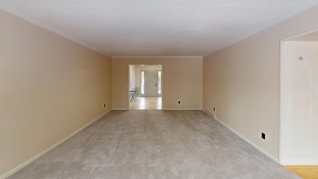 spare room featuring a textured ceiling, light colored carpet, and crown molding