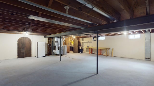 basement featuring heating unit and white fridge