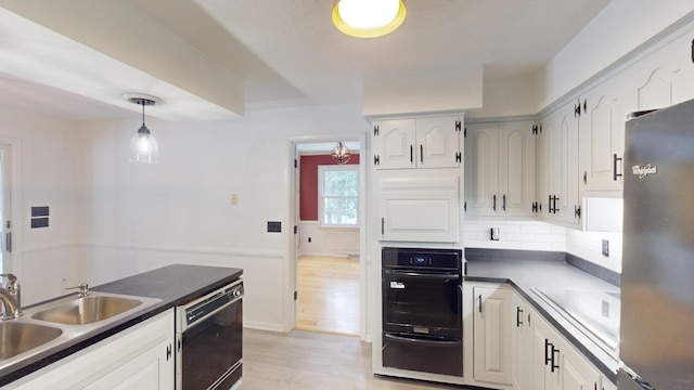 kitchen with pendant lighting, sink, white cabinetry, and black appliances