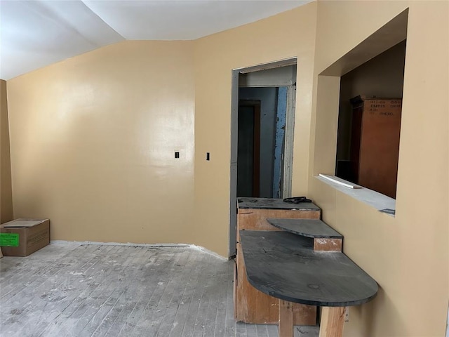 hallway featuring lofted ceiling and wood finished floors