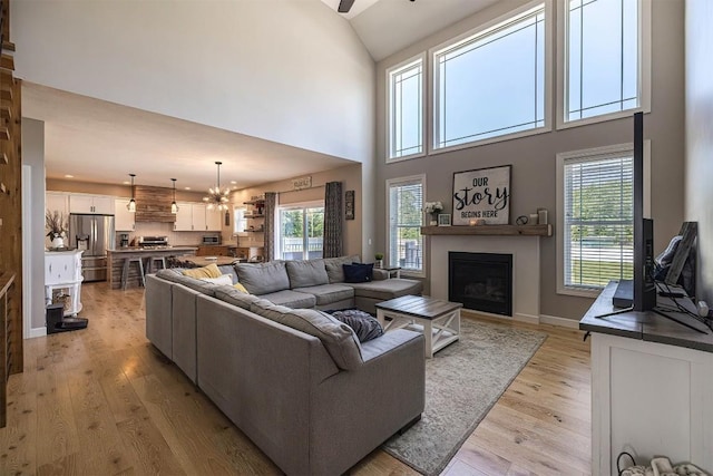 7662 Magnolia Bnd, Fairview, PA 16415 - living area featuring light wood-style floors, a fireplace, a high ceiling, plenty of natural light, and a ceiling fan