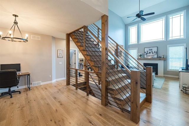 7662 Magnolia Bnd, Fairview, PA 16415 - stairs with a glass covered fireplace, wood finished floors, a chandelier, healthy amount of natural light, and a high ceiling