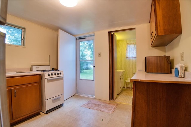 12199 Mantor St, Conneaut Lake, PA 16316 - kitchen featuring white gas range oven, light countertops, and brown cabinetry