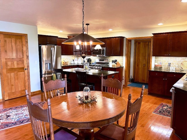 dining space with recessed lighting, light wood-style flooring, and a notable chandelier