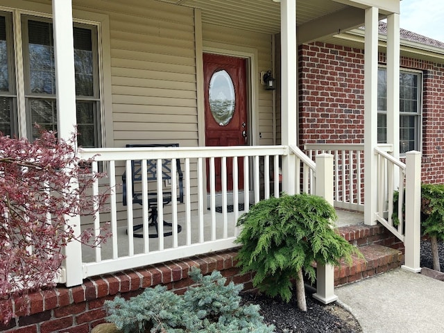 property entrance featuring covered porch and brick siding