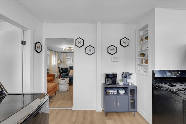kitchen featuring built in features, a chandelier, light wood finished floors, gas stove, and range