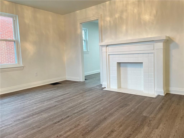 unfurnished living room with dark hardwood / wood-style flooring and a tile fireplace